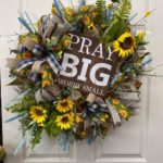 sunflower wreath with a wooden sign that says pray big