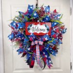 patriotic themed mesh wreath with red, white, and blue ribbon and blue florals