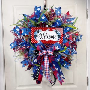 patriotic themed mesh wreath with red, white, and blue ribbon and blue florals