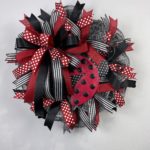 wreath with black and white mesh, black, red, and white ribbon, and a ladybug wreath attachment