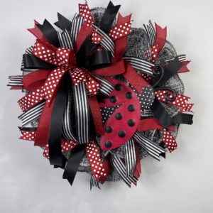 wreath with black and white mesh, black, red, and white ribbon, and a ladybug wreath attachment