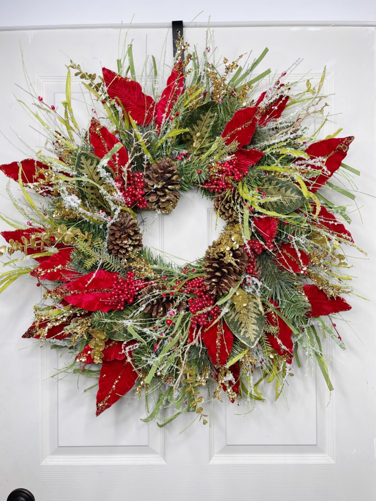 grapevine wreath with poinsettia leaves, pinecones, and greenery 