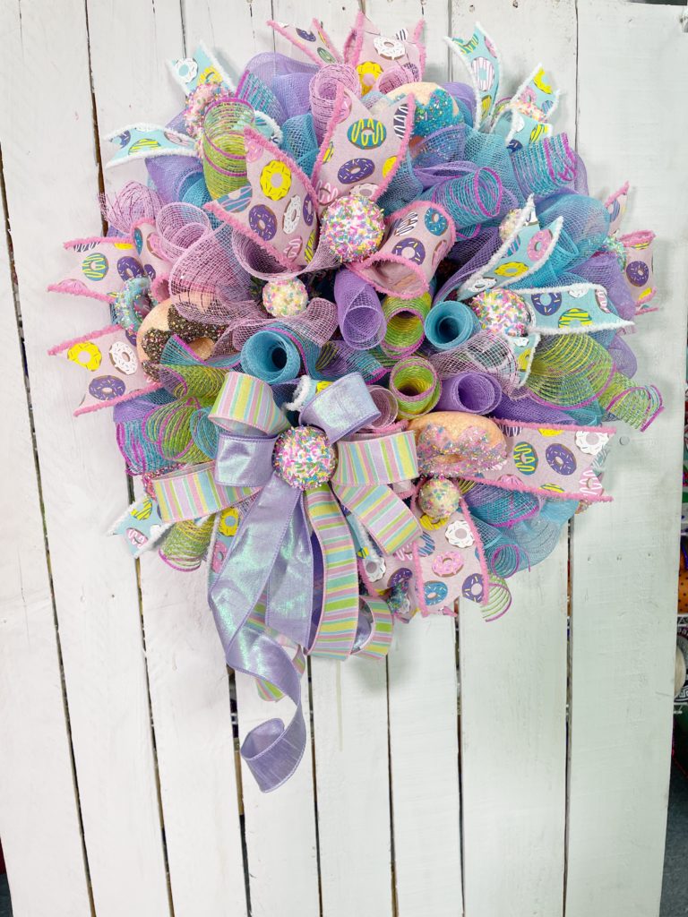 Evergreen wreath with pastel colored deco mesh and fake donuts and cake pops