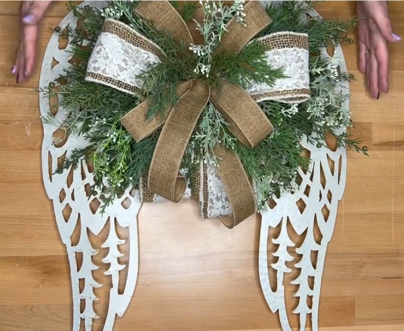 metal angel wings with greenery stems and a bow