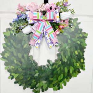 A faux boxwood wreath door hanger decorated with pastel florals and a colorful multi-ribbon bow. The greenery is shaped into a classic wreath silhouette, topped with pink, purple, and white florals.