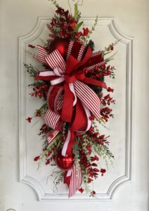 Christmas themed swag with large bow and red flowers.