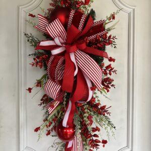 Christmas themed swag with large bow and red flowers.