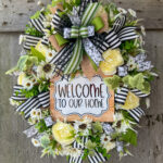 Oval wreath with with welcome to our home sign, flower blooms, and ribbon.