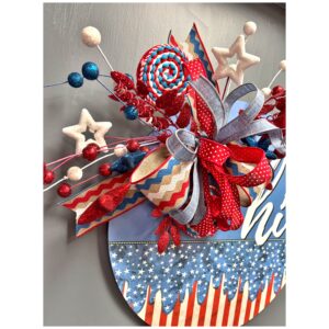 Angled side view of the door hanger showcasing the dimensional design of the bow and the playful placement of glittered embellishments including stars and berries.