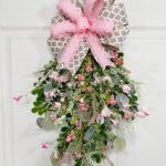 Full view of the completed pink and green berry swag, showing a cascading floral arrangement with pink berries, greenery, and a two-ribbon bow at the top.